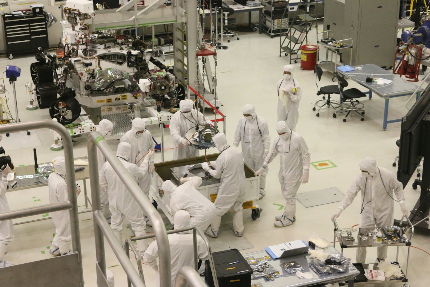 Ingenieros ensamblan un vehículo robótico complejo en un laboratorio de sala limpia.